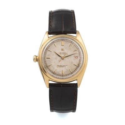 a gold plated rolex wrist watch with black leather strap