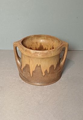 a brown cup sitting on a table with a handle