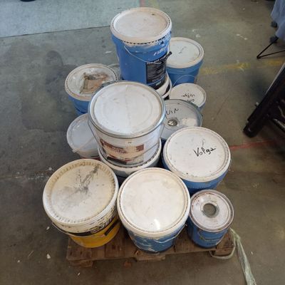 plusieurs seaux de peinture posés sur une palette dans un garage