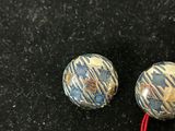 pair of blue and white buttons on a black surface with a price tag