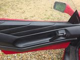 the interior of a red car with the door open and the driver ' s seat down