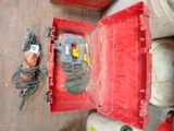 une boîte rouge contenant des outils, posée sur le sol