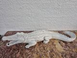 une statue représentant un alligator blanc assis sur une table