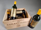 two bottles of wine in a wooden box next to a bottle of wine