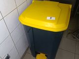 a yellow and black trash can in the corner of a bathroom