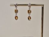 a pair of earrings on a stand with a marble block in the background