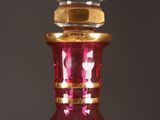 a red glass bottle with a gold rim sitting on a table