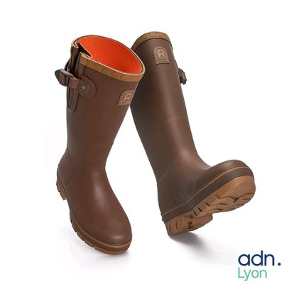 une paire de bottes en caoutchouc marron avec une doublure orange sur fond blanc