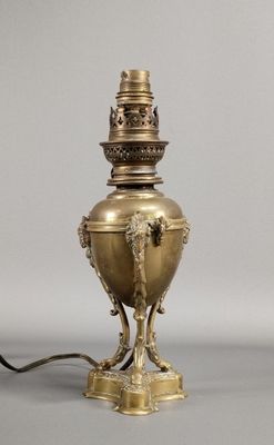 une lampe ancienne en laiton surmontée d'une tête de lion