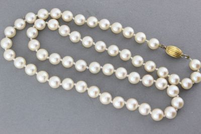 Gros plan sur un collier de perles blanches avec un fermoir en or