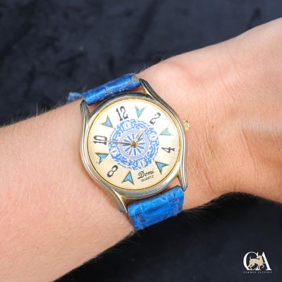 une personne portant au poignet une montre avec un bracelet bleu