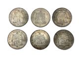 six silver coins of different sizes and shapes on a white background