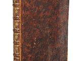 an old book with a brown cover sitting on top of a white surface