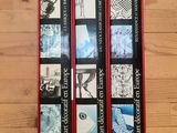 trois livres dans un étui rouge posé sur une table en bois