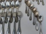 many silver spoons and forks arranged together on a table