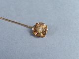 an image of a gold flower broochle on a blue surface
