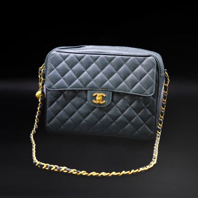 a black chanel bag with gold chain on a black background