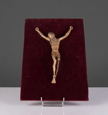 une image représentant un crucifix en or posé sur un socle en velours rouge