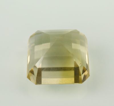 un gros plan d'une pierre de quartz vert facettée posée sur une surface blanche