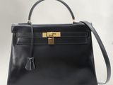 a black leather handbag with a gold lock on the handle