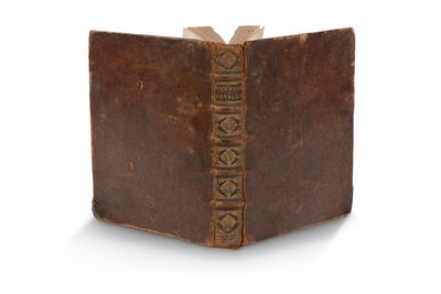 un vieux livre à la couverture brune posé sur une surface blanche