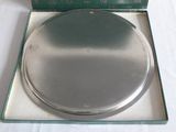 a silver plate in a green box on a white table