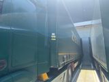 two green semi trucks parked side by side in a parking lot