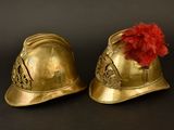 pair of gold helmets with red pom poms on them