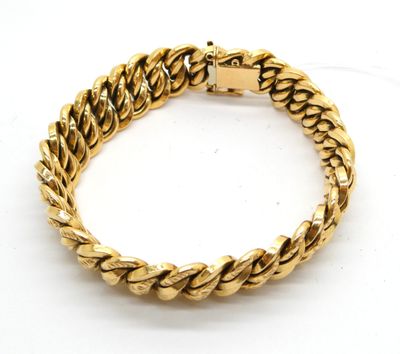 un bracelet en or jaune présentant un motif tressé sur fond blanc