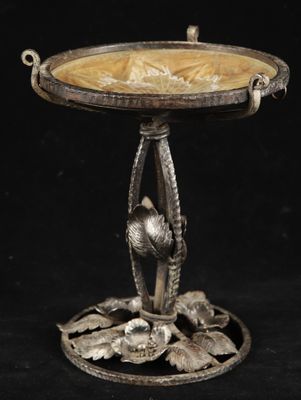 an antique silver plate with a bird on it on a stand