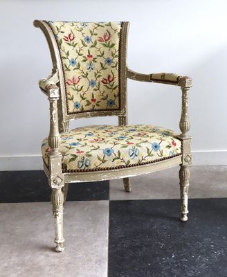une chaise dont l'assise est recouverte d'un tissu à motifs floraux, posée sur un sol à carreaux noirs et blancs
