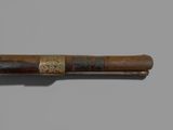 a close up of a pipe with a wooden handle on a gray surface