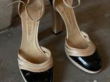 pair of black and white high heeled shoes sitting on a cement floor