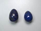 two blue lapis stone beads on a white surface