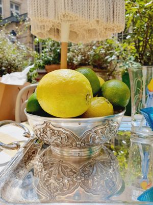 a silver bowl filled with lemons and limes on a table