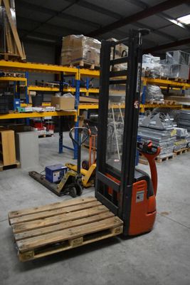 a forklift in a warehouse with pallets on the floor