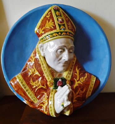 une figurine en céramique représentant un pape tenant une rose