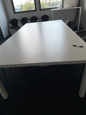 une table blanche sur laquelle se trouve un stylo, dans une pièce