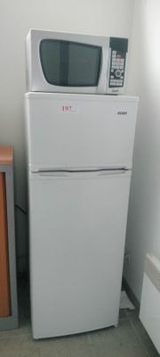 a microwave on top of a refrigerator in a small room