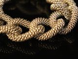 a close up of a gold chain bracelet on a black surface