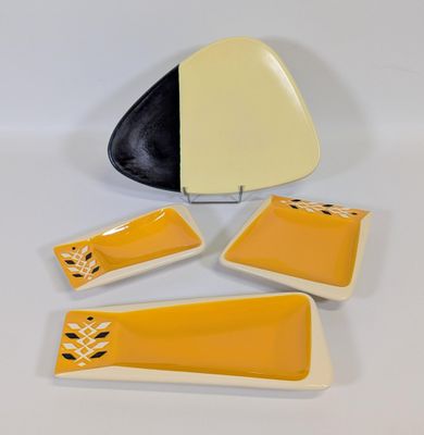 un lot de quatre plats jaunes et noirs, accompagné d'une assiette noire et blanche