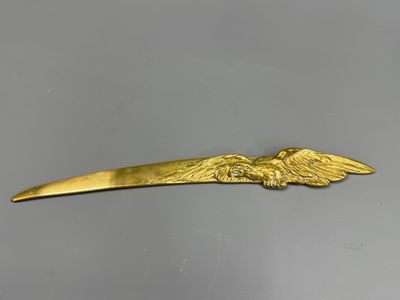 un gros plan d'une barrette en forme d'aigle doré posée sur une surface grise