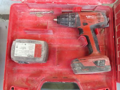 une boîte à outils rouge contenant une perceuse et deux autres outils