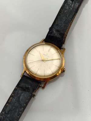 gros plan d'une montre sur une surface blanche avec un bracelet noir