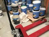many buckets of paint sitting on the floor next to a pallet