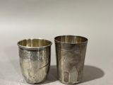 pair of antique silver plated shot glasses on a white surface