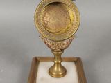 une image représentant une petite horloge en laiton posée sur un socle en marbre