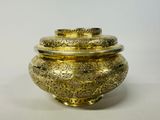 a gold vase with a lid on a white surface