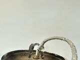 a metal bowl with a water faucet in it on a table