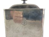 a silver container with a handle and a hand on it
